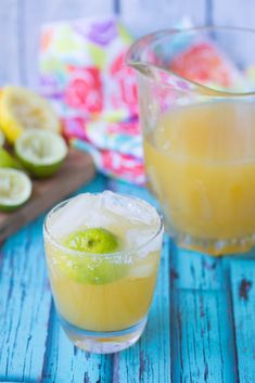 two glasses filled with lemonade next to sliced kiwis on a blue wooden table