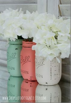 three painted mason jars with flowers in them