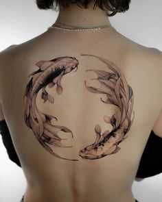 a woman's back with two koi fish tattoo on it