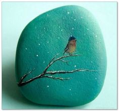 a painted rock with a small bird on it's back sitting on a tree branch