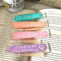 four bookmarks that are sitting on top of an open book, with coffee mug in the background