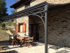 an outdoor dining area in front of a house with stone walls and brick roofing