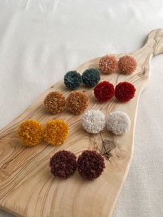 a wooden board with several different colored pom poms on it and a white sheet behind it