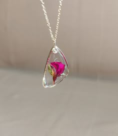 a necklace with a pink flower inside of it