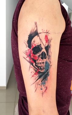 a woman's arm with a skull and paint splattered on the side