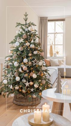 a christmas tree with white and gold ornaments in a living room next to a couch