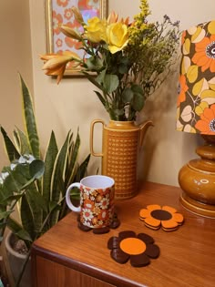 there is a vase with flowers in it next to two mugs and some cookies