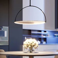 a round table with flowers on it in front of an open kitchen and dining room area