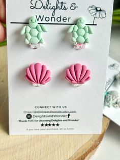 pink and green sea shell earrings on white card with handwritten text delight & wonder