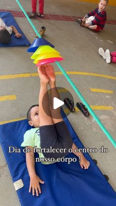 a little boy laying on top of a blue mat in front of other kids sitting down