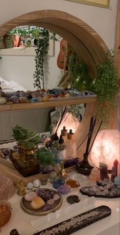 there is a mirror that has many items on the table in front of it, including rocks and plants