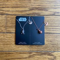 the star wars necklaces are on display in front of a card with two charms