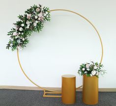 two yellow vases with flowers on them sitting in front of a circular wall decoration