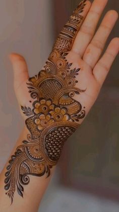 the hand is decorated with henna and flowers on it's palm, as well as an intricate pattern