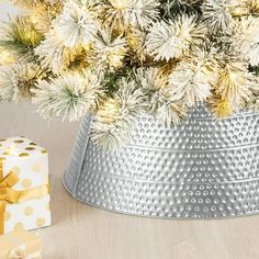 a christmas tree in a silver bucket with gold polka dots on it and a gift box