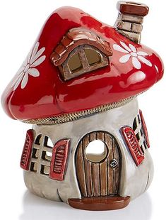 a red and white mushroom house with flowers on it's roof, sitting in front of a white background