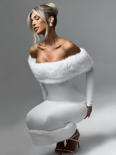 a woman in white is sitting on the ground wearing high heels and a fur stole around her neck