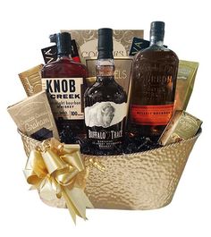 a gift basket filled with liquor bottles and chocolates, wrapped in gold ribbon bow