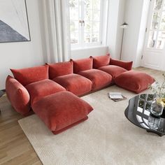 a large red couch sitting on top of a wooden floor next to a glass table