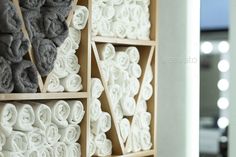 towels are stacked on wooden shelves in a room with mirrors and lights behind them - stock photo - images