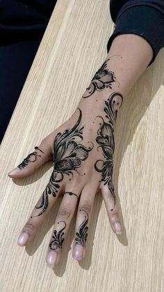 a woman's hand with hennap on it sitting at a wooden table