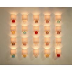 several lit candles are arranged in rows on the wall, each with different shapes and colors