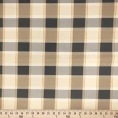 a large plaid fabric with black and tan squares on it's side, next to a ruler