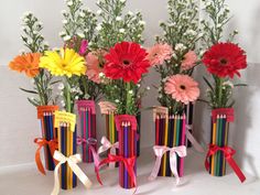 four vases filled with colorful flowers and pencils