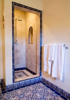 a bathroom with blue and white tiles on the floor, shower stall and towel rack