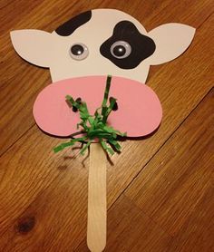 a paper cow on a stick with green leaves