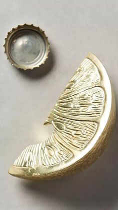 a gold brooch with a bottle cap next to it