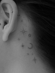 a woman's behind the ear tattoo with stars and moon