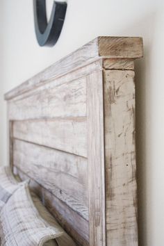 a bed with a wooden headboard next to a white wall and a black metal hook on the wall