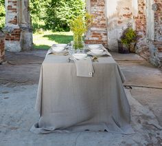 the table is set with plates and silverware on it, in front of an old brick building