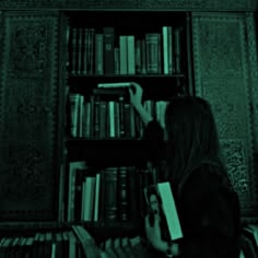 a woman sitting in front of a book shelf filled with books