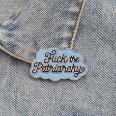 a blue enamel pin with the words flick the patriarchy on it's back