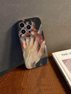 an iphone case sitting on top of a wooden table next to a book and magazine