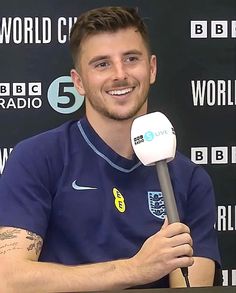 a man holding a microphone in front of a black wall with the words world cup on it