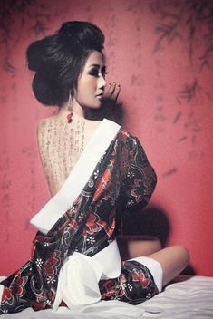 a woman sitting on top of a bed next to a red wall