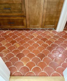 a bathroom with red and white tiles on the floor next to a wooden cabinet door