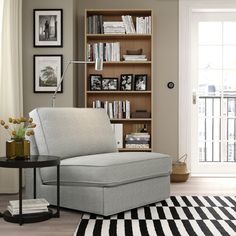 a living room with a gray chair and bookshelf in the corner, next to a black and white striped rug