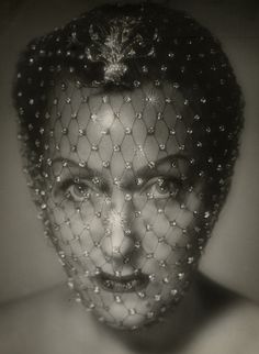 an old photo of a woman wearing a veil and pearls on her head, with the image in black and white