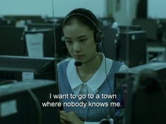 a woman with headphones on looking at her cell phone in an office setting that says, i want to go to a town where nobody knows me