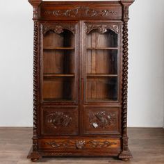 an old wooden bookcase with carved carvings on the front and sides, sitting on a hard wood floor