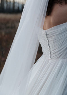 the back of a bride's wedding dress, with her veil blowing in the wind