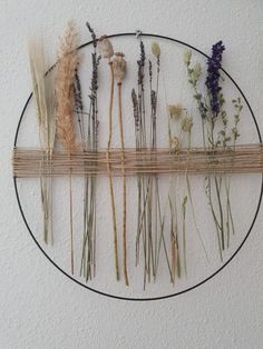 dried flowers are arranged on a round metal frame hanging on the wall in front of a white wall