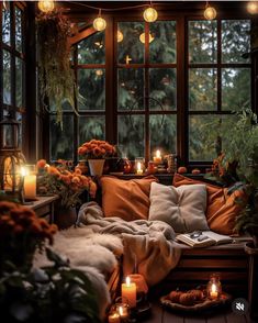 a cozy room with candles and flowers on the windowsill