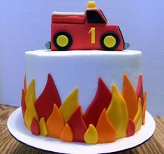 a birthday cake with a firetruck on top and flames coming out of it