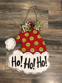 a red and green christmas ornament hanging on a wood floor with the words ho ho ho