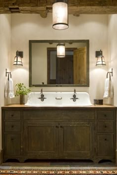 a bathroom with a sink, mirror and lights on the wall next to an area rug